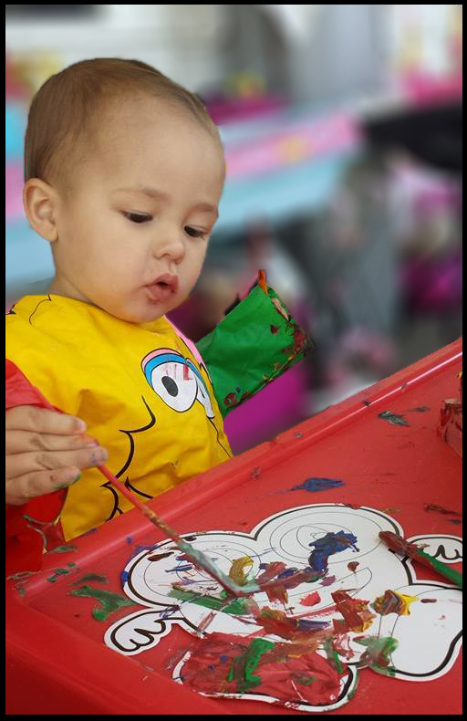 Young, Autistic participant engaging in our 'Living Through Art' session. Front view of a participant painting with acrylics.